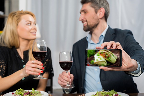 Man showing smartphone near woman with glasses wine